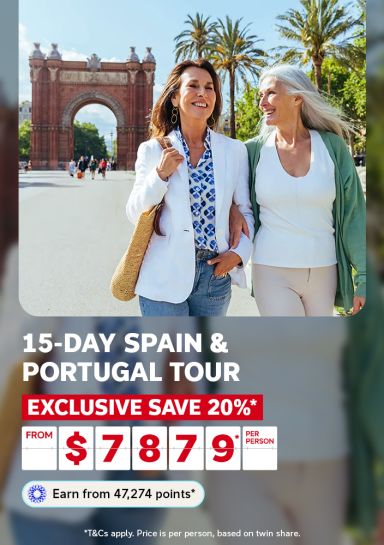 Two women walking arm in arm past the Arc de Triomf in Barcelona for a 15-day Spain and Portugal tour saving 20% from $7879 per person