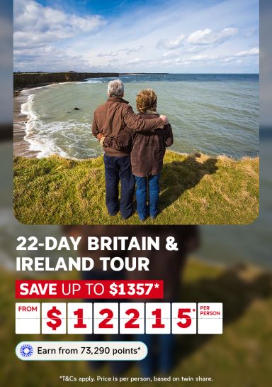 Couple on a rugged coastal cliff overlooking a sweeping Irish bay for a 22-day Britain and Ireland tour saving up to $1357 from $12215 per person