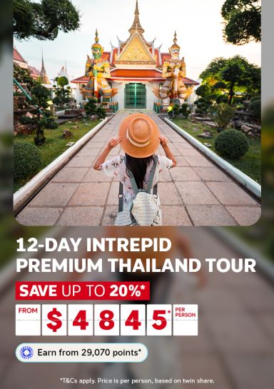   Traveller in a sun hat approaching the giant guardians of Wat Arun Bangkok for a 12-day Intrepid Premium Thailand tour saving up to 20% from $4845