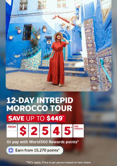 Woman in red dress admiring vibrant blue alley in Chefchaouen for a 12-day Intrepid Morocco tour saving up to $449 from $255 per person