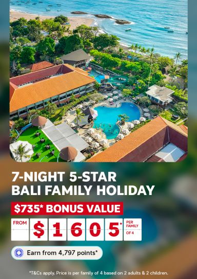 Aerial view of a resort pool water slide and gardens beside a Bali beach for a 7-night family holiday with $735 bonus value from $1605 per family of 4