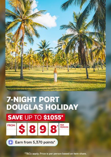 Woman walking through a sunlit coconut palm grove for a 7-night Port Douglas holiday saving up to 1055 dollars from 898 per person