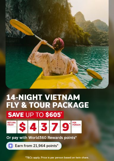 Woman kayaking through calm waters beneath limestone karsts for a 14-night Vietnam fly and tour package saving up to $605 from $4379 per person