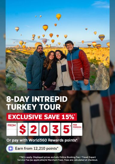 Group of friends smiling together as hot air balloons rise over Cappadocia for an 8 day Intrepid Turkey tour saving 15 percent from 2035 per person