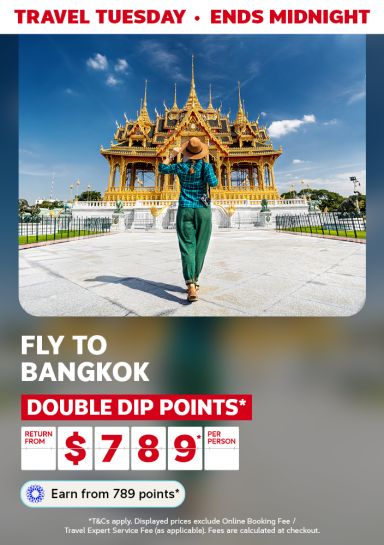 Traveler walking toward golden Thai temple for Travel Tuesday return flights to Bangkok from $789 per person with double dip points