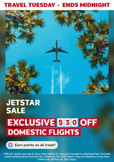 Travel Tuesday - ends midnight | Jetstar sale - exclusive $30* off domestic flights | Earn points on all travel* | *$30 off Jetstar one-way & return fares within AU> Discount included in advertised fare. Excludes online booking fee & merchant fee. Limited to first 1,000 tickets. May be withdrawn at any time. Online only 26 May 26. T&CS apply. | Plane flying overhead framed by palm trees