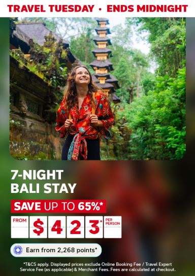 Woman smiling, hiking through a jungle next to a temple in Bali featuring a 7-night Bali stay from $423