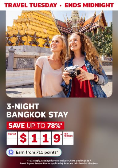 Women smiling, holding a camera next to the temple in Thailand featuring a 3-night Bangkok stay from $119