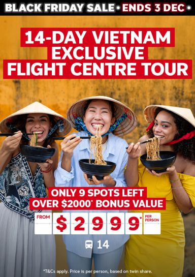 14-day Vietnam exclusive Flight Centre Tour | only 9 spots left! Over $2000* bonus value - from $2,999* per person | three people smiling eating noodles in front of a yellow wall