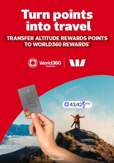 Hand holding a rewards card with two hikers celebrating atop a misty mountain summit for transferring Altitude Rewards points to World360 Rewards