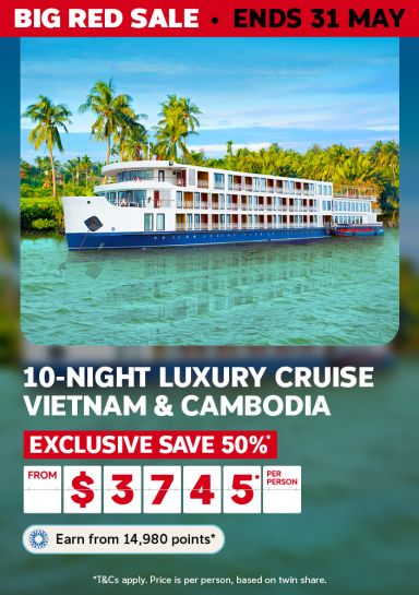   Luxury river cruise ship on turquoise tropical waterways lined with palms for a 10-night Vietnam and Cambodia cruise saving 50% from $3745 per person