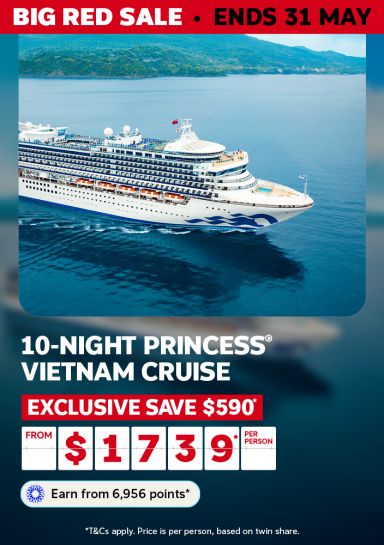 Large Princess cruise ship sailing calm blue waters past a lush green coastline for a 10-night Vietnam cruise saving $590 from $1739 per person