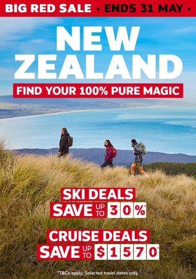 Hikers on golden tussock above a sweeping New Zealand coastal bay for a Big Red Sale with ski deals saving 30% and cruise deals saving up to $1570