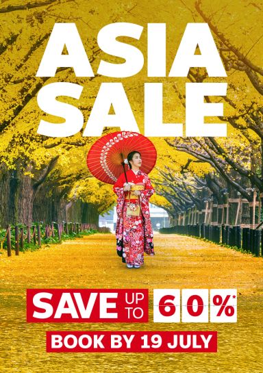 Woman in a pink kimono walking through yellow autumn leaves in Japan