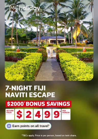 Palm lined garden path leading to a fountain and resort villa at dusk for a 7 night Fiji Naviti escape with $2000 bonus savings from $2499 per person