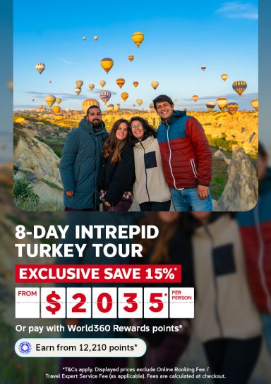 Friends smiling as hot air balloons rise over Cappadocia at sunrise for an 8-day Intrepid Turkey tour saving 15 percent from 2035 per person