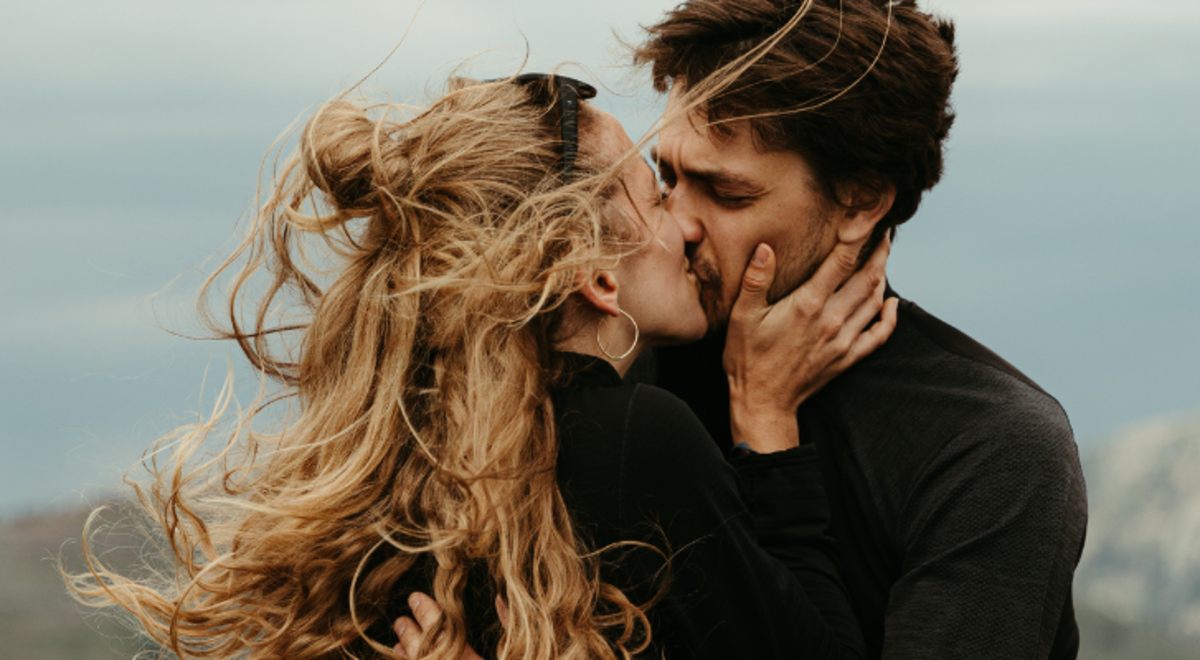 Couple kissing on top of a mountain 