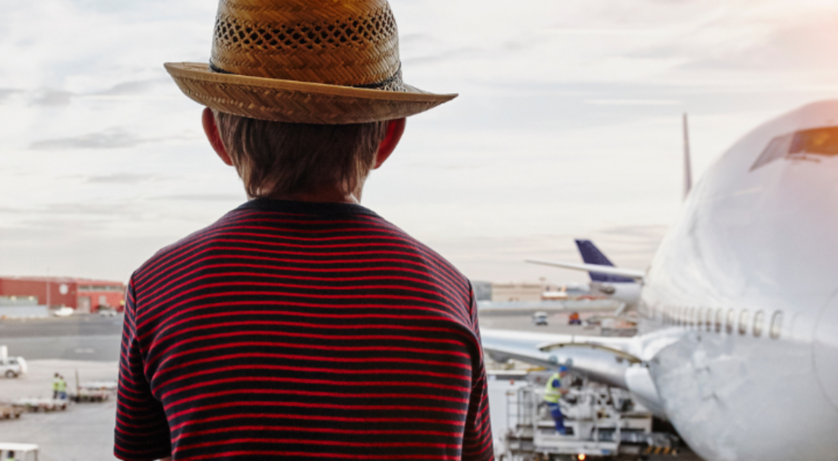 Young boy sitting in the airport looking out to the landed planes 