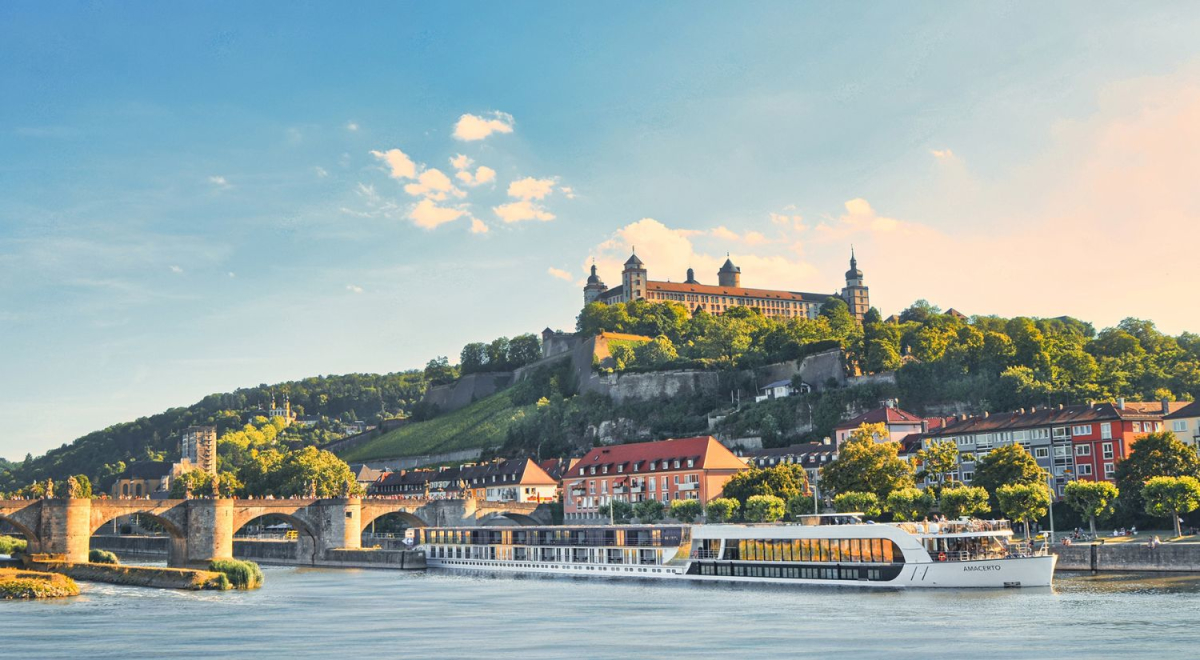 A cruise ship sailing along a river running through a charming town