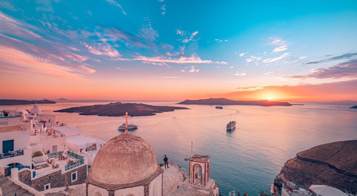 View from the top of Santorini overlooking buildings and the ocean as the sun sets