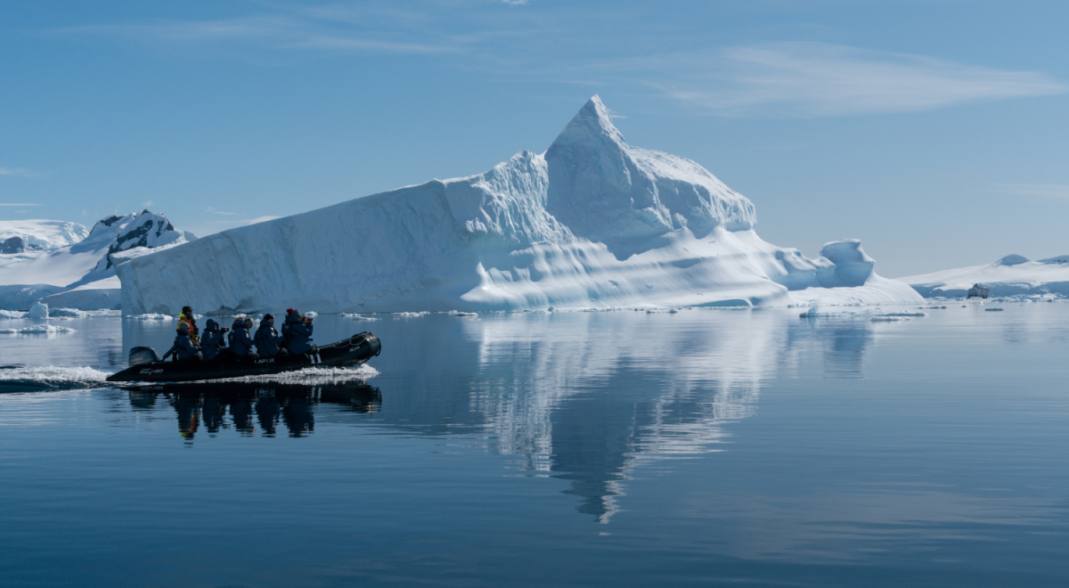 Expedition travellers cruising past towering icebergs in a zodiac boat near the Antarctic Peninsula