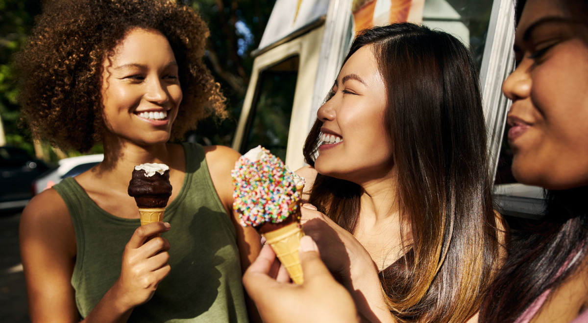 Cropped shot of a group of female friends eating ice cream outside