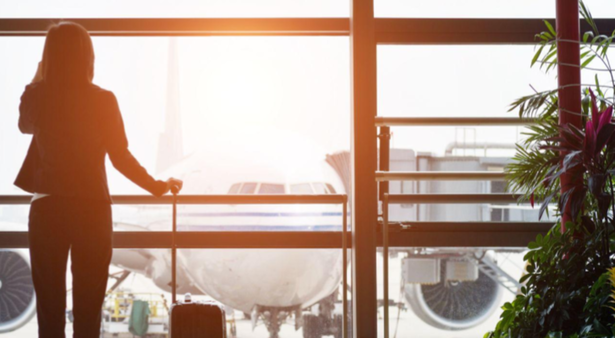 woman watching a plane in airplane when talking at phone and holding a luggage