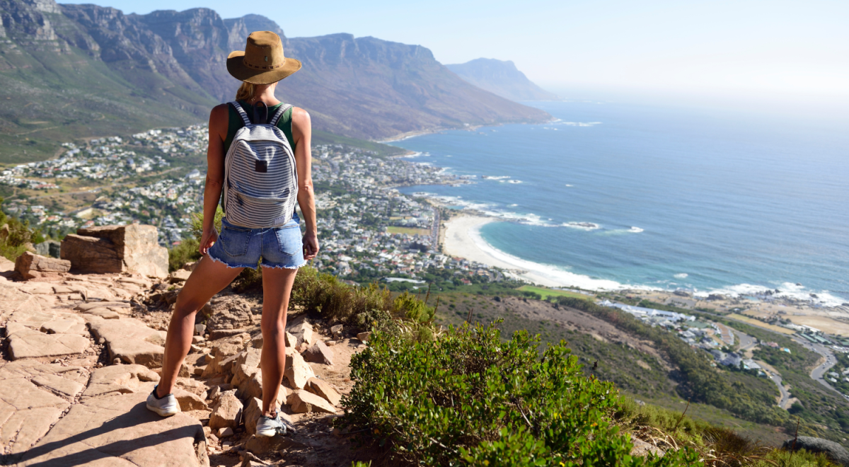 South Africa, Cape Town, woman standing looking at the coast during hiking trip to Lion's Head
