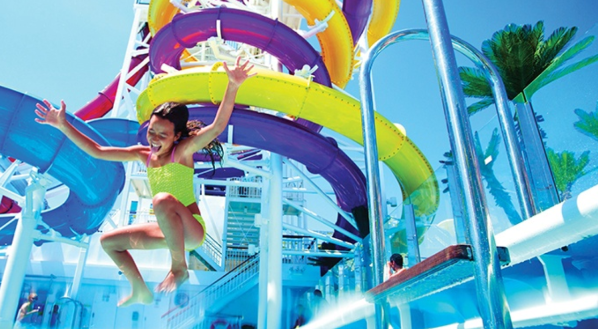 A girl jumps into a pool in a waterpark on board a cruise ship