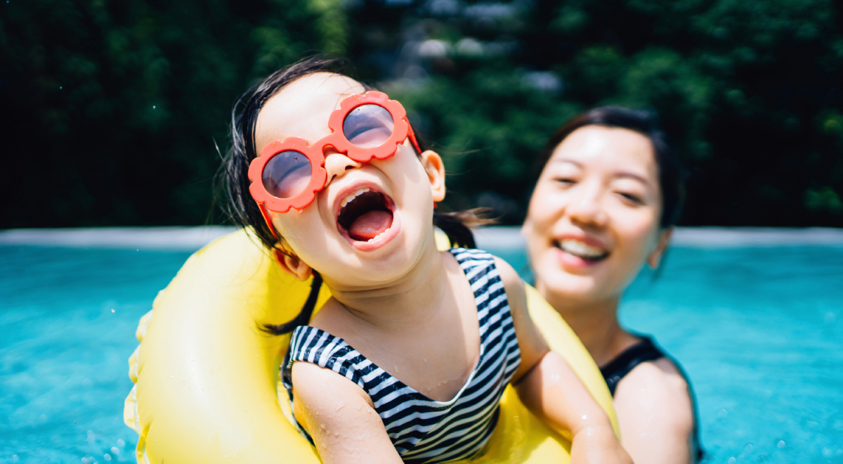Happy toddler playing in pool with mum