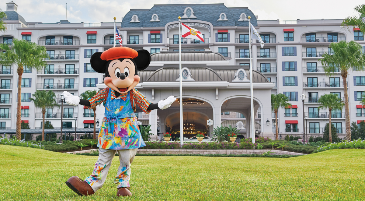 Mickey Mouse dressed as a painter posing on the lawn in front of Disney's Riviera Resort