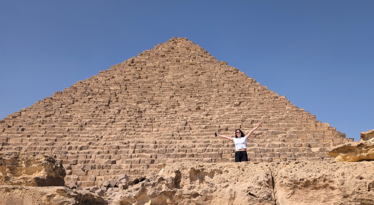 Sara Winfield stands and waves from below one of the Great Pyramids of Giza