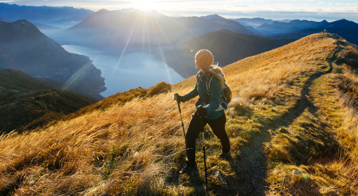 Woman hikes along ridgecrest above lake, valley
