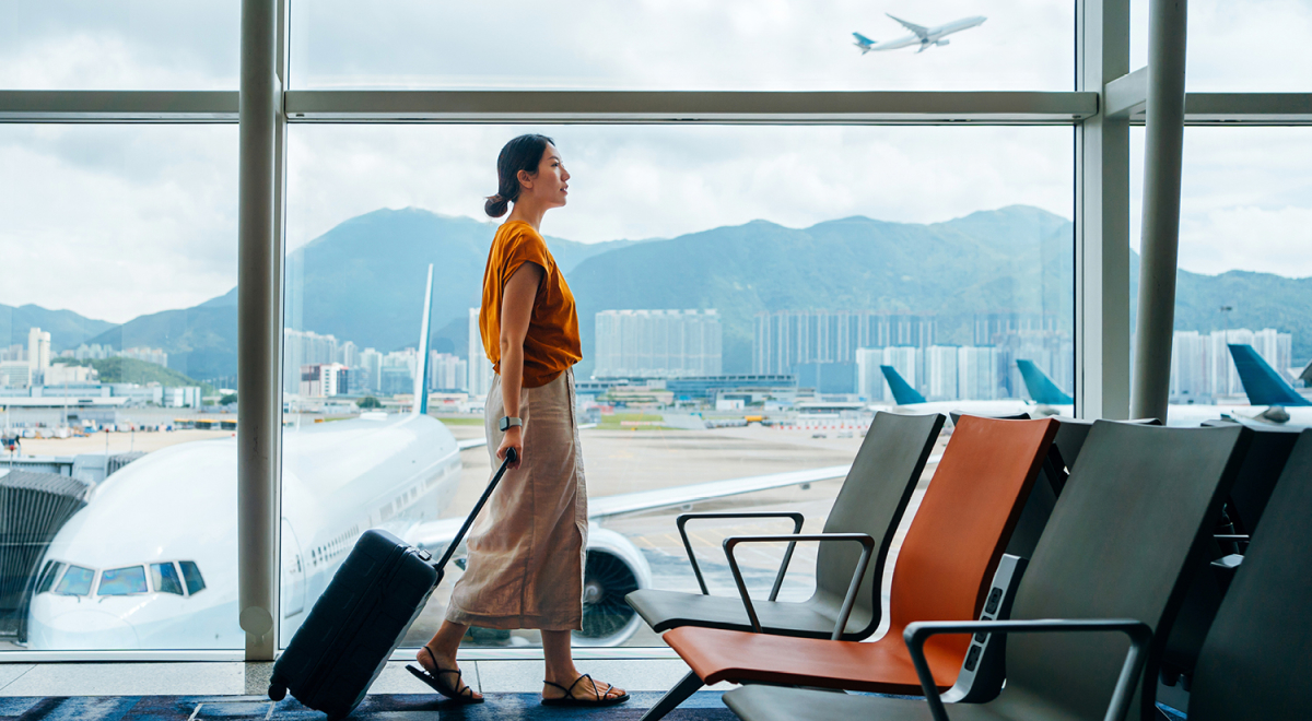 A woman walking through the airport with a rolling suitcase