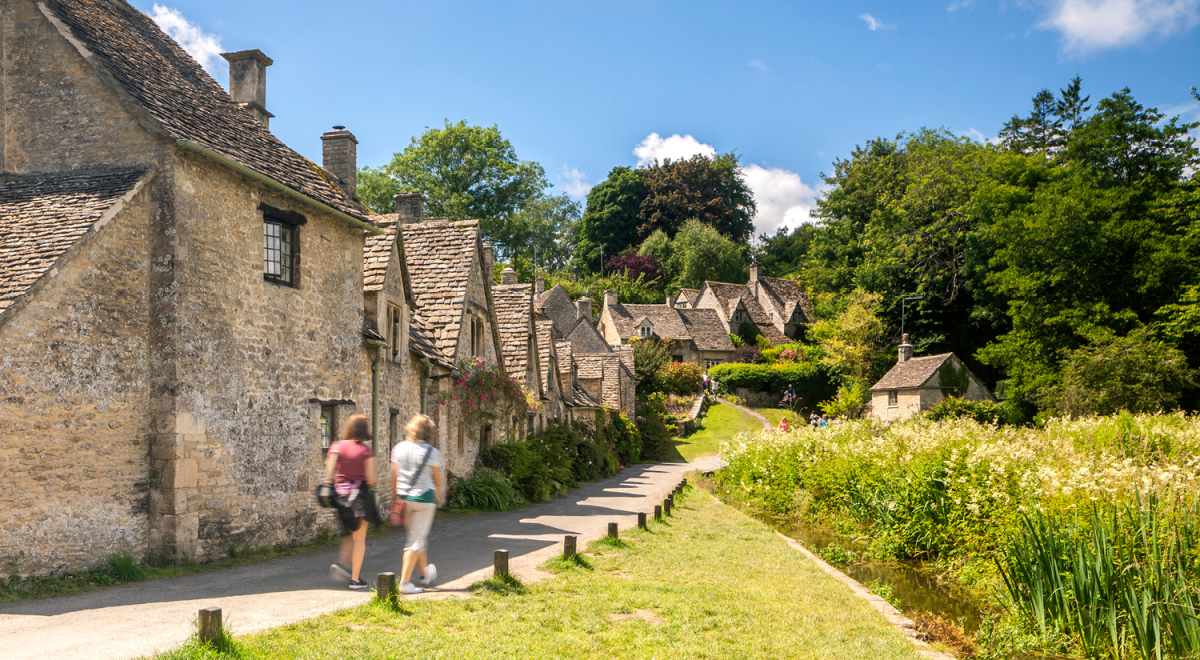 Two people walking along Arlington Row in Bibury, England