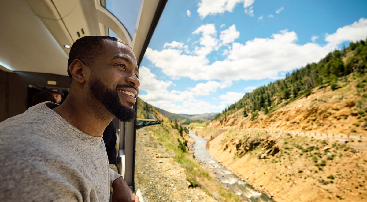 A person looking out the train window on a Rocky Mountaineer voyage