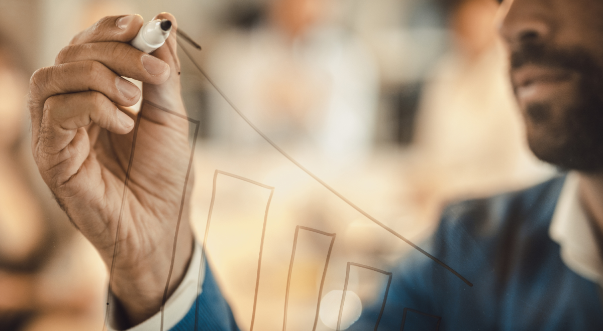 Close up of a businessman drawing diagram of progress on a glass wall.