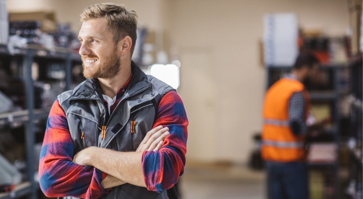 A man in a warehouse smiles and looks outside