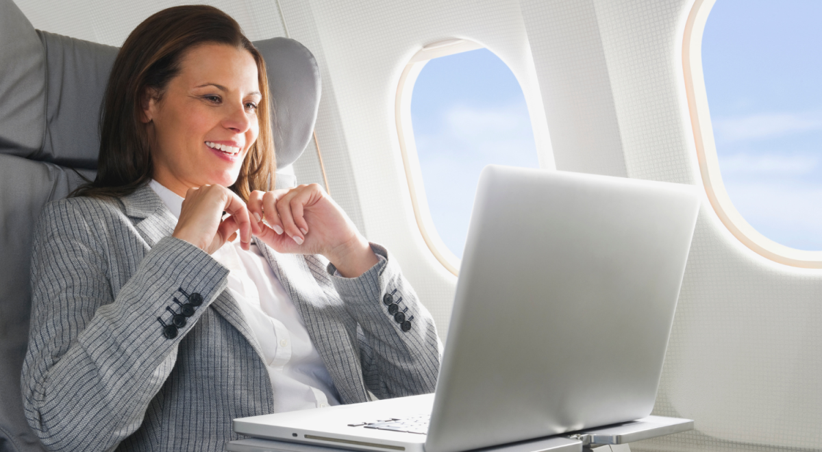 Business woman using laptop while seated in business class of a plane
