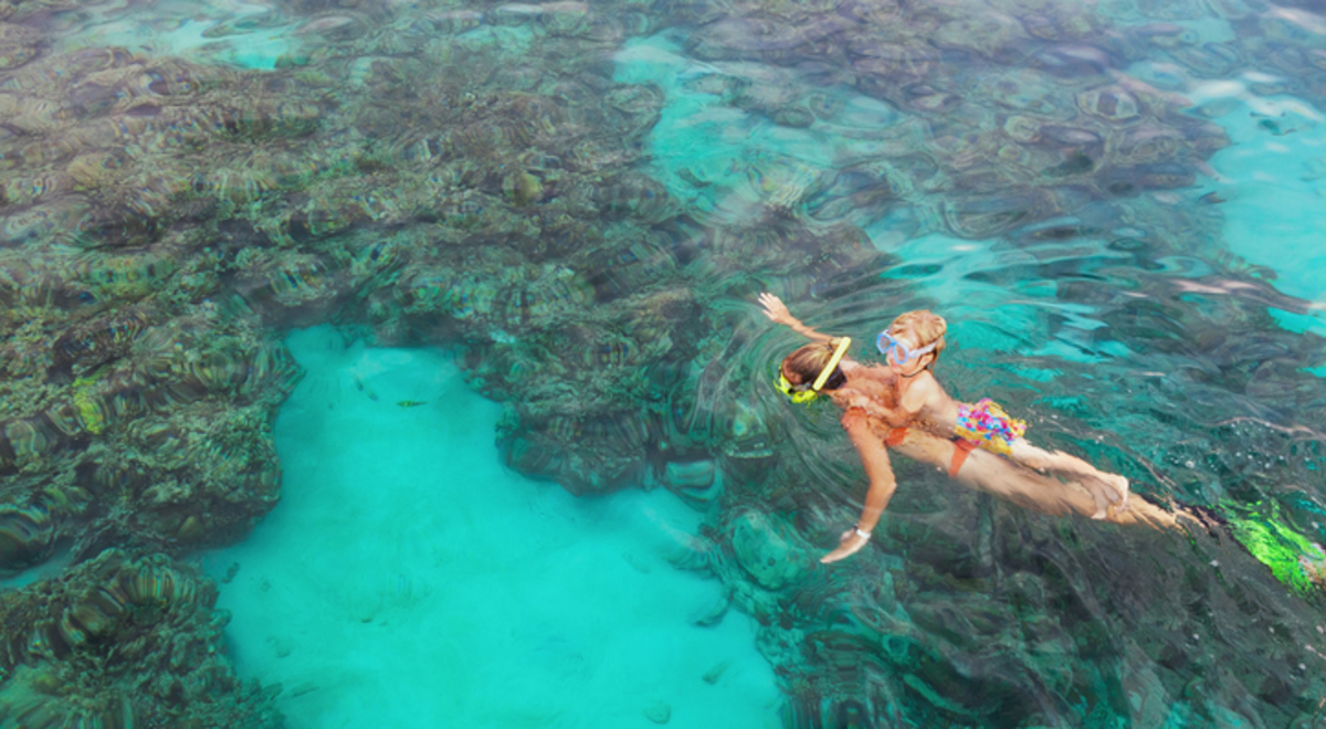 Mother, kid in snorkeling mask dive underwater with tropical fishes