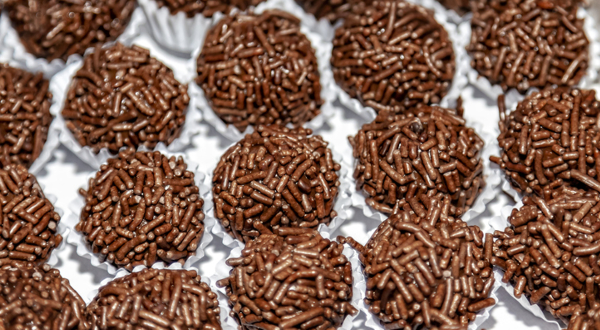 Seen from above, on a white tray, packed in white paper forms are some chocolate sweets called brigadeiro in Brazil.
