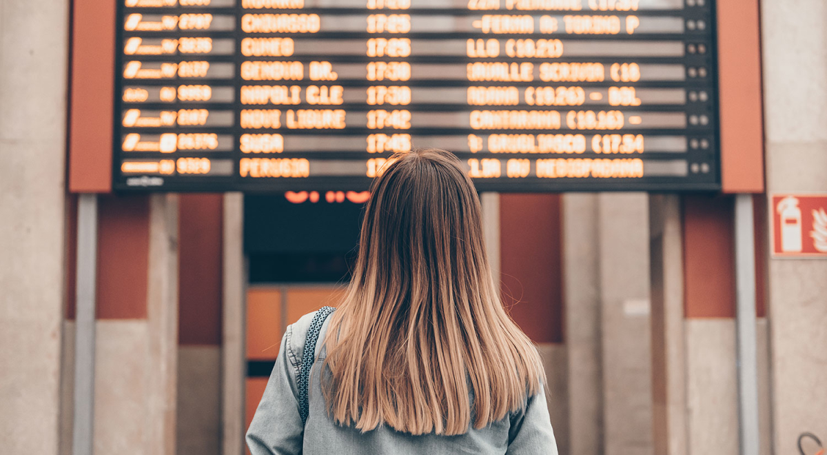 Woman in front of airport departures board