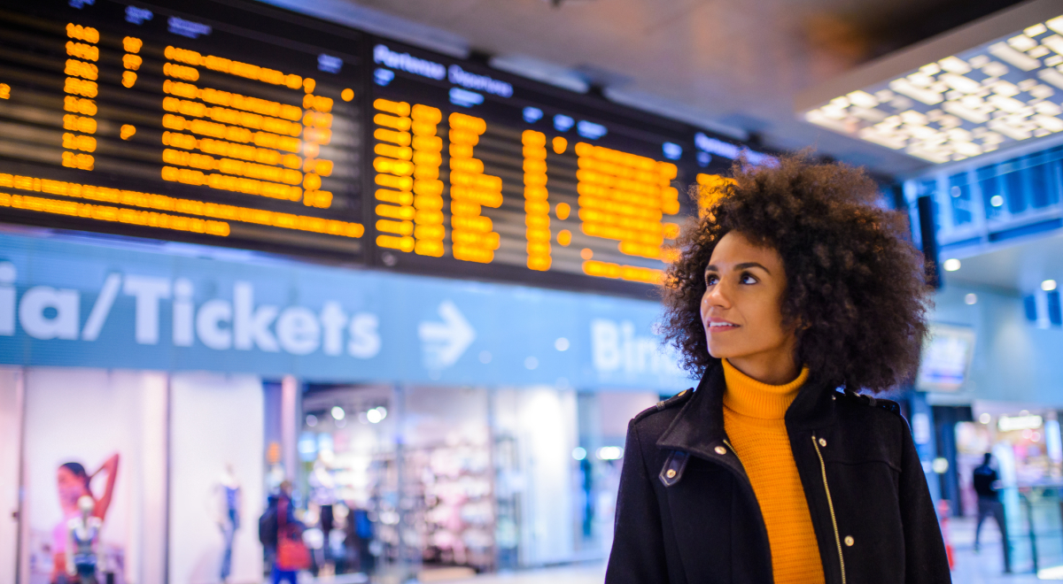 Smiling woman using mobile phone at the airport.