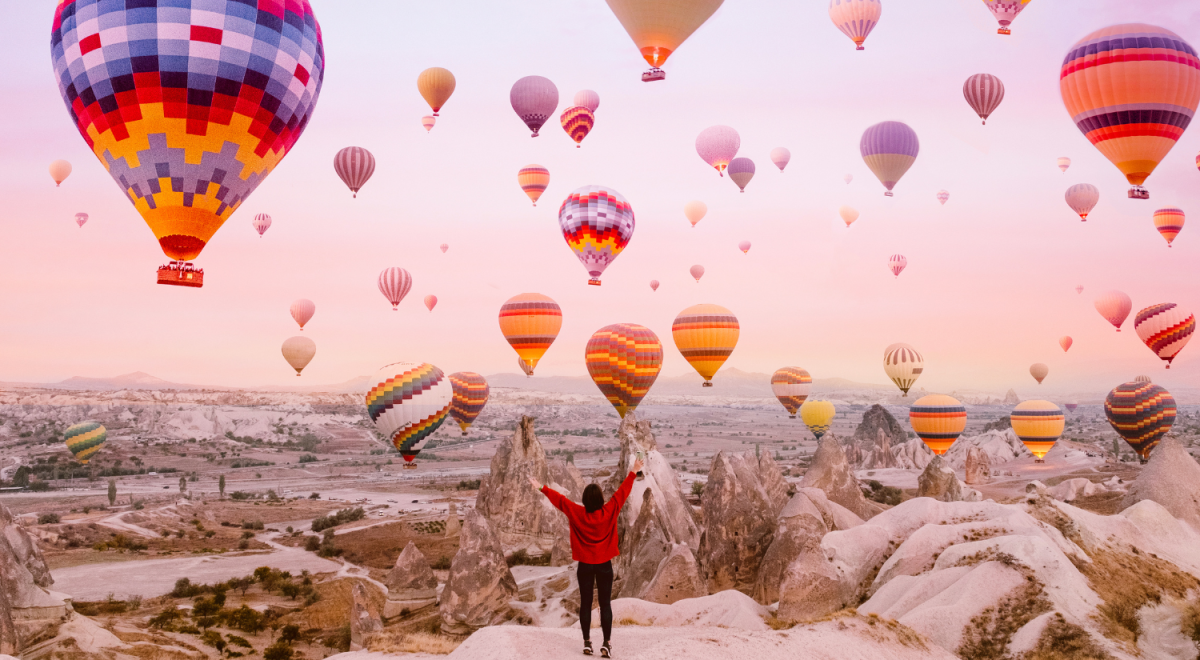 A woman watches a sky full of hot air balloons in Cappadocia, Turkiye