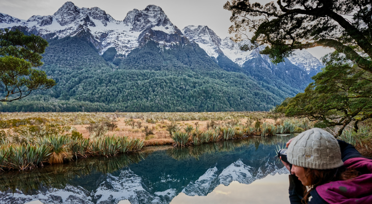 Girl photographing Mirror Lakes and Earl Mountains, Fiordland National Park
