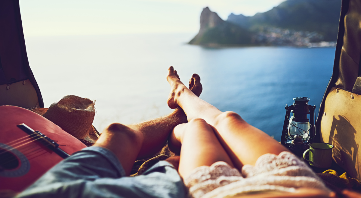 The entwined legs of a man and a woman lying somewhere overlooking a beautiful bay