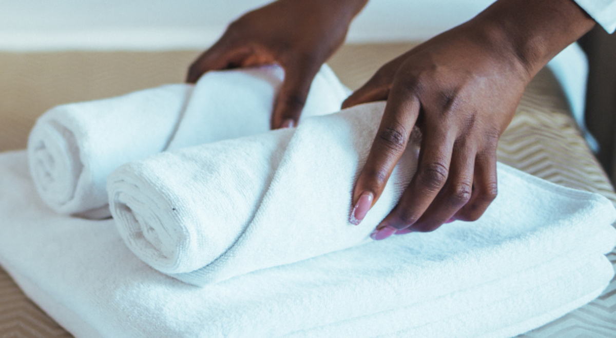 Lady holding folded towels in a hotel room