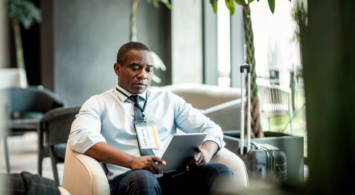 Business man wearing a suit and visitor tag working on a tablet