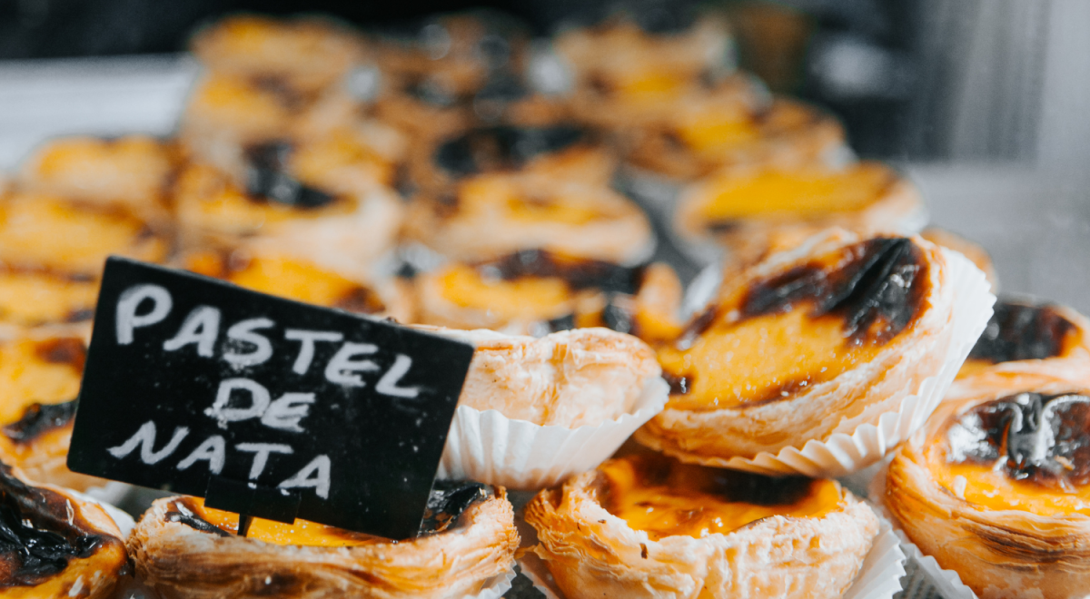 Portuguese custard tarts displayed in paper cups with a little sign saying "Pastel De Nata"