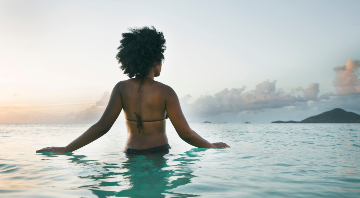Woman in the ocean looking at far off islands